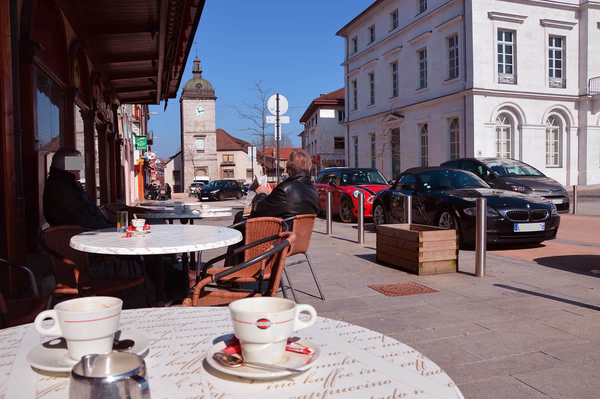 Two coffee cups on a sunny sidewalk café table