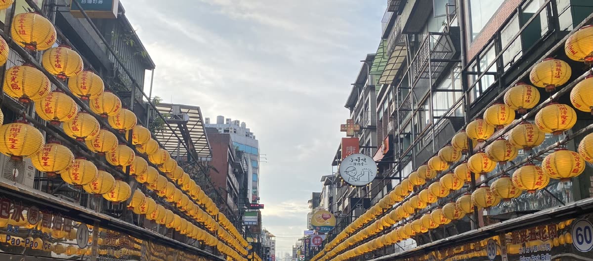 Rows of glowing yellow lanterns above a busy night market street